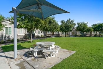 A picnic table with an umbrella on the grass